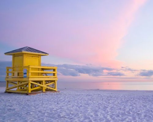 Yellow lifeguard tower on a pastel beach.