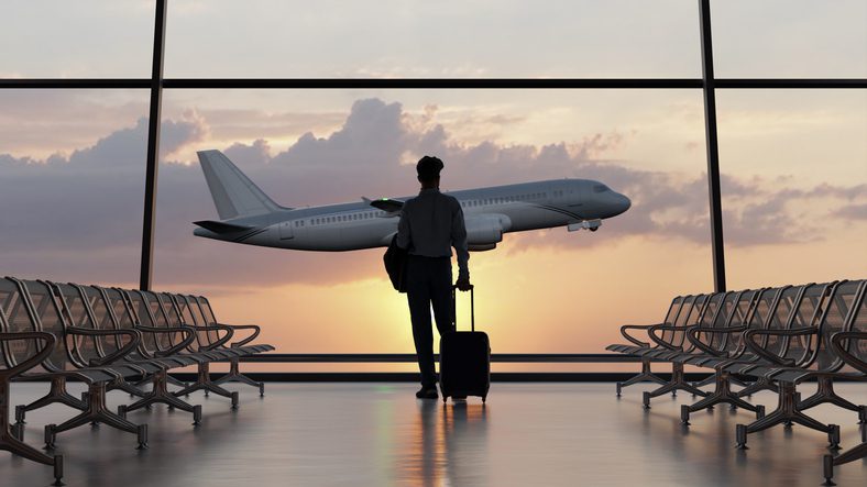 Traveler watching airplane at airport window.
