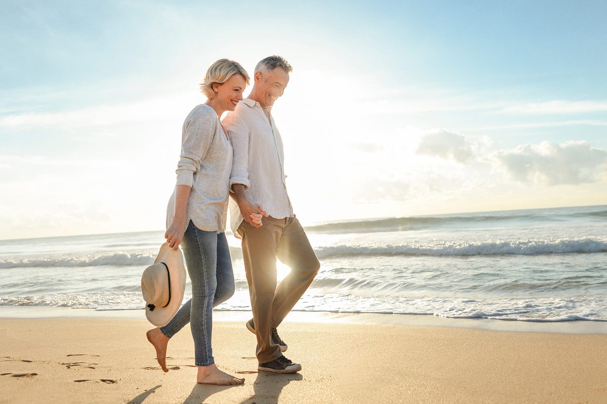 Couple walking on beach at sunset.